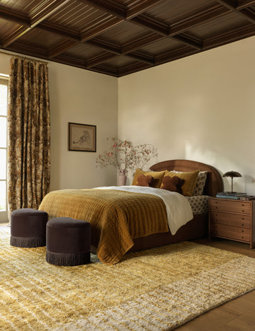 #color::ochre #size::6--x-9- #size::8--x-10- #size::9--x-12- #size::10--x-14- #size::12--x-15- | A bedroom featuring the Bhari thick organic design hand-knotted wool rug.