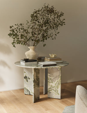 Celia round dining table styled with various books and a large sculptural vase filled with botanicals.