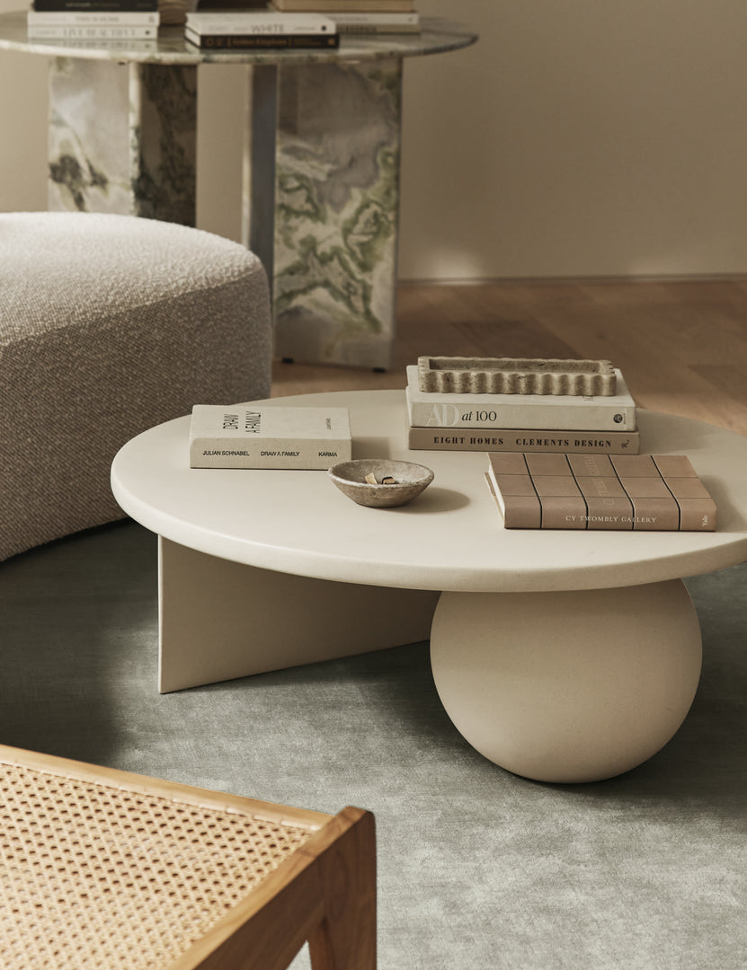 #color::ivory | Amaya round sculptural cement coffee table styled in a living room.