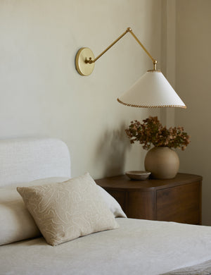 Arroyo Mixed-Material Adjustable Arm Sconce by Elan Byrd styled above a bedside table.