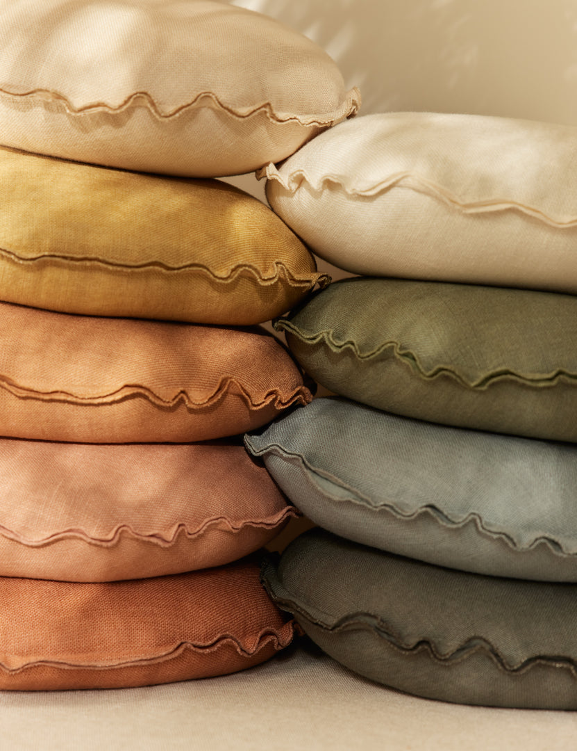 | All colors of the Arlo linen flange trim round pillows stacked together.