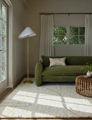 Arroyo Mixed-Material Floor Lamp by Elan Byrd styled next to a green velvet sofa in a living room.