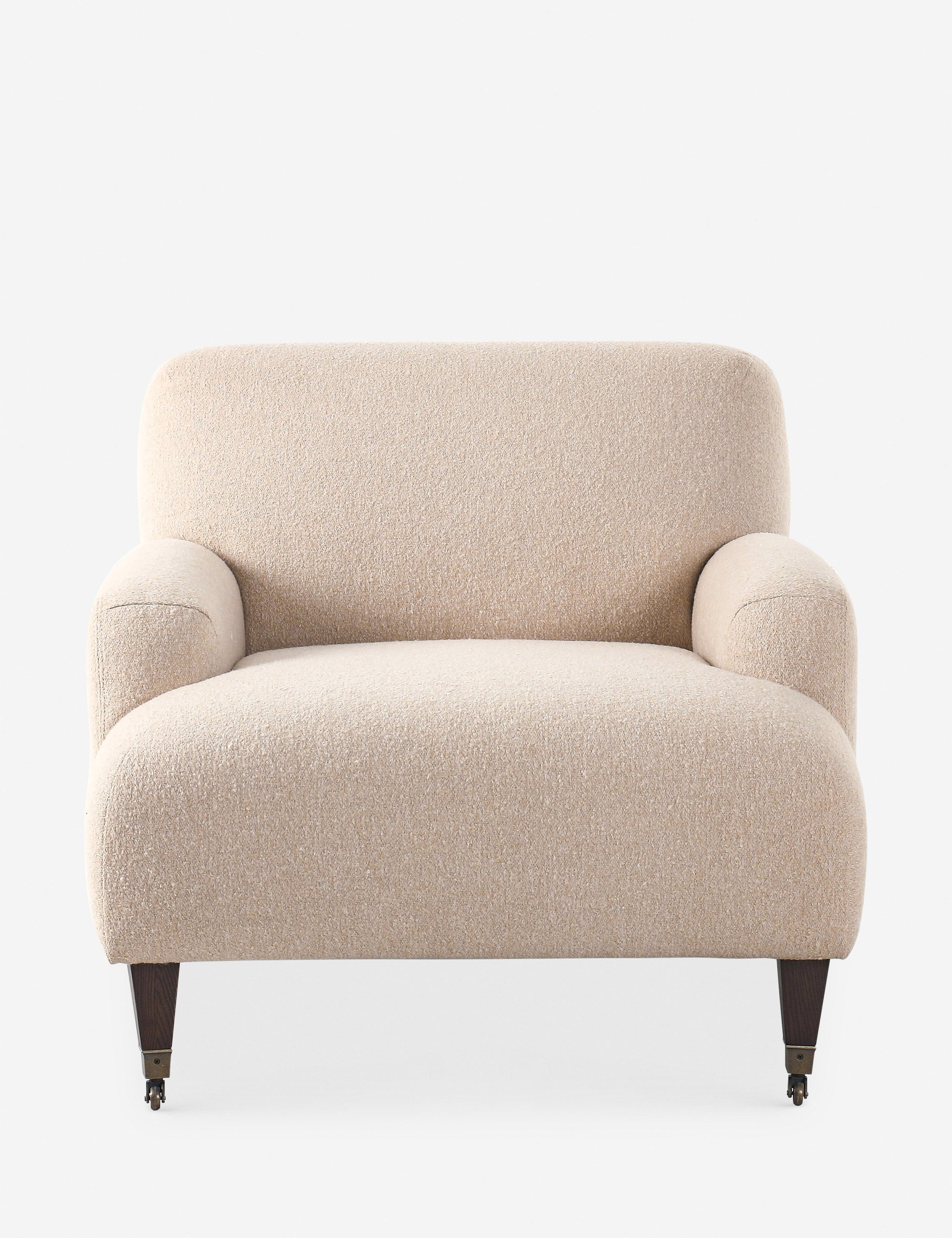 Beige textured boucle armchair with rounded back and arms on dark wooden tapered legs with casters.