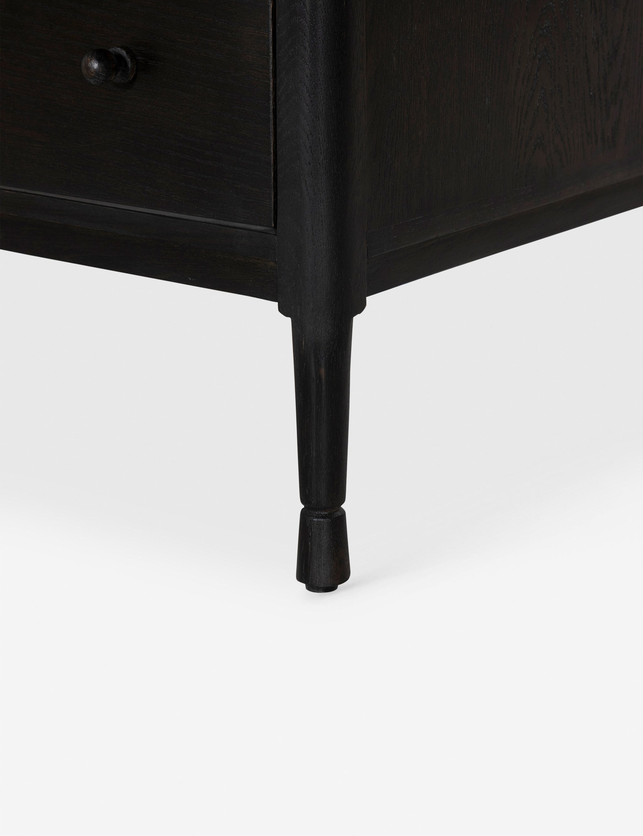 Close-up of a tapered wooden leg on an espresso dresser.