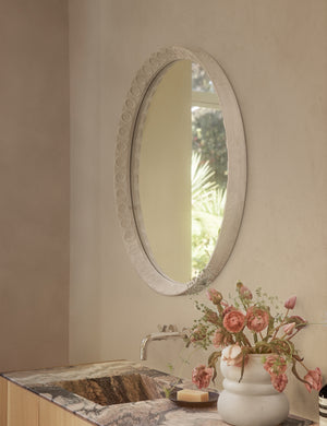 Correa round distressed wood frame wall mirror hanging above a bathroom vanity.