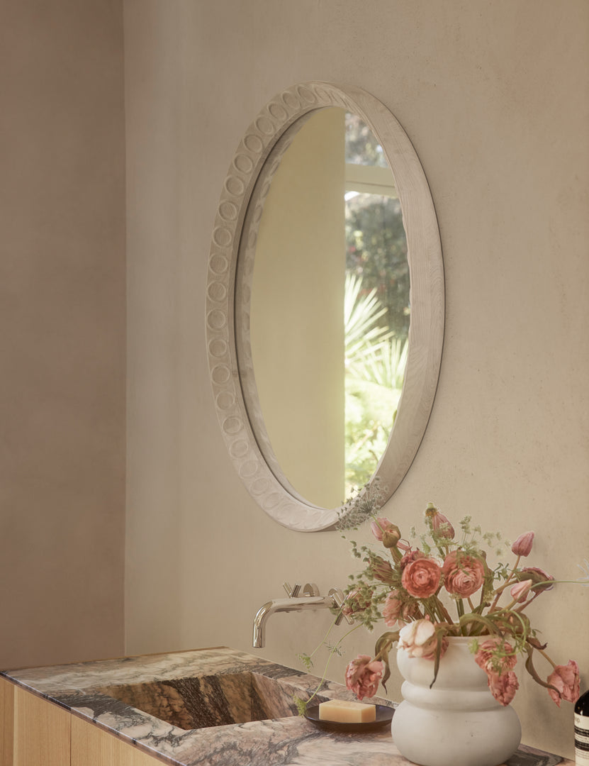 #color::natural | Correa round distressed wood frame wall mirror hanging above a bathroom vanity.