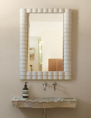Munro white sculptural modern wall mirror hung above a bathroom sink.