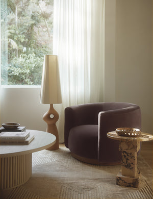 Lowry rounded silhouette velvet accent chair styled with a round orange marble side table and sculptural floor lamp.