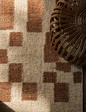 Close up view of the Mosaic Handwoven Wool Rug by Elan Byrd underneath a rattan coffee table.