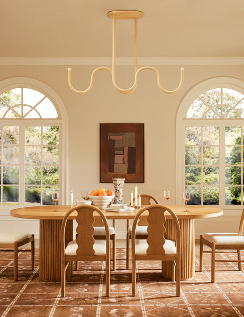 | Noor sculptural, wavy linear chandelier hanging above a dining table