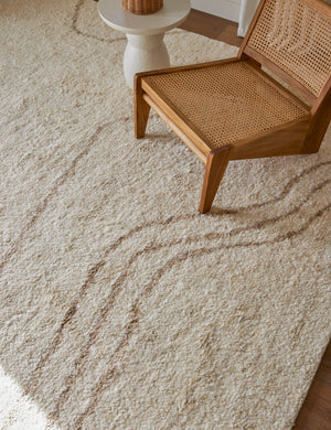 Currents Hand Knotted Wool Rug by Elan Byrd paired with a cane accent chair and white side table.