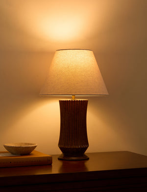 Alta fluted ceramic base table lamp by Heidi Caillier with the light turned on