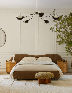 Kukka large modern wavy arm chandelier in bronze hanging in a bedroom over the bed
