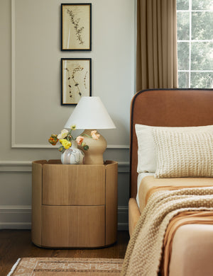 Bedroom with the Raphael modern rounded natural wood two drawer nightstand next to a rust velvet upholstered bedframe