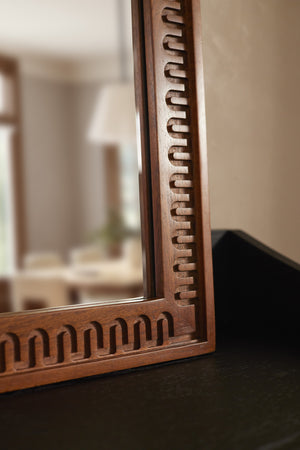 Close up bottom corner view of the Dane carved wood framed mirror