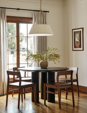 Mojave round minimalist dining table in black styled with solid walnut dining chairs and a pleated shade pendant light.