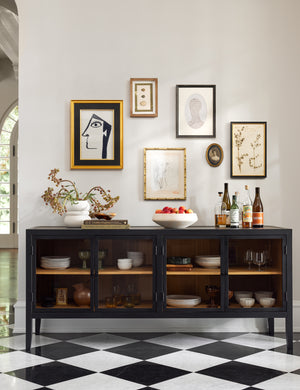 Morey glass front black curio sideboard cabinet styled as a bar cabinet accented by a wall art galley wall above