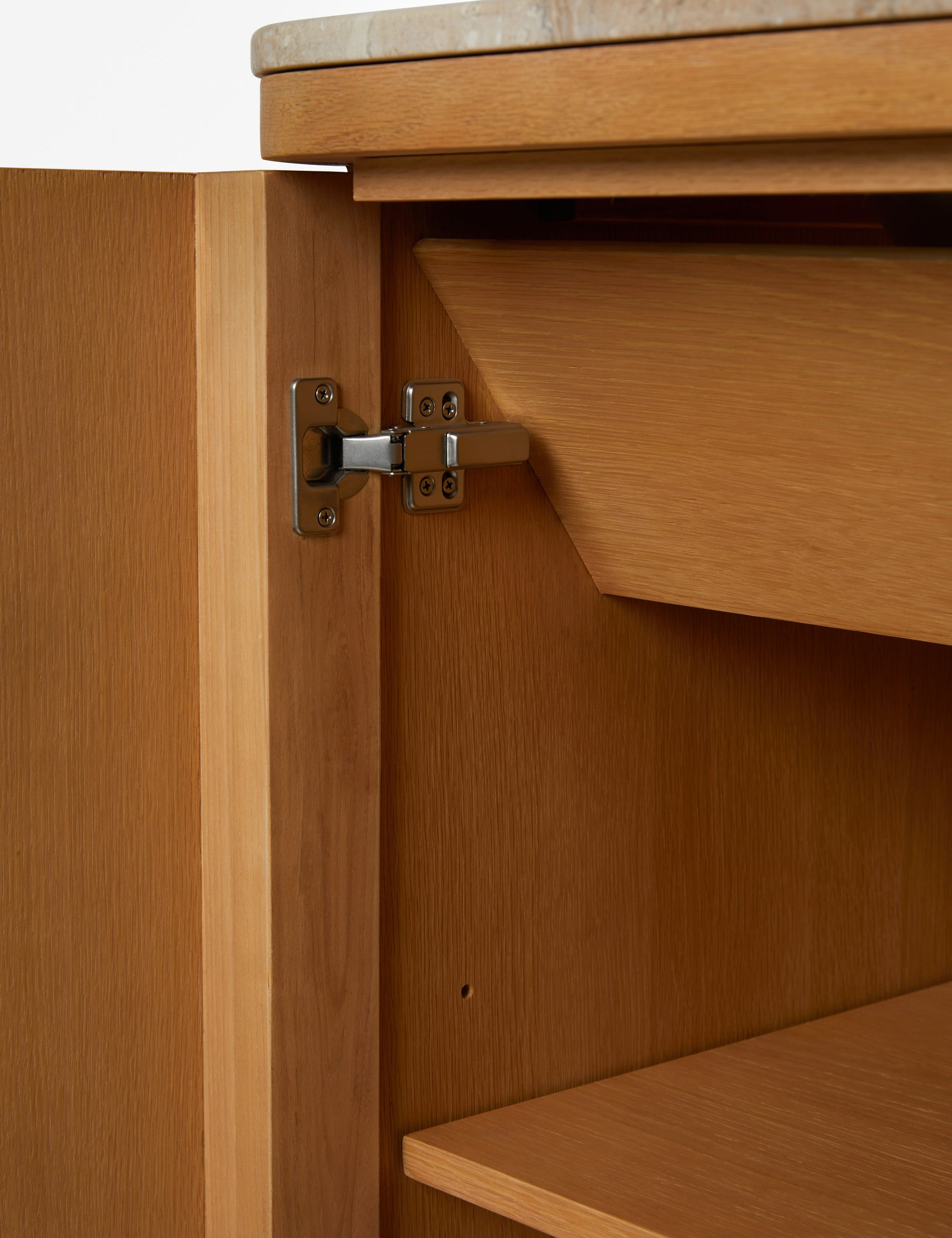 Close-up of two small, dark metal knobs on a light wood vanity cabinet.