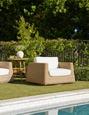 Aisha wide arm modern wicker outdoor swivel chair by the side of a pool.