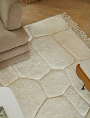 Close up of the Kivi raised cobblestone pattern fringe wool area rug styled under a sofa
