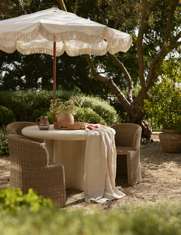 #color::natural | Three Mettam modern wicker outdoor dining chair styled with a round outdoor dining table with a white umbrella.