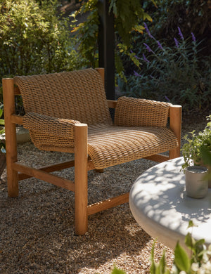 Gally wicker and teak outdoor accent chair in an outdoor lounge space.