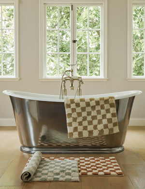 Two-tone checkerboard bath mat by Sarah Sherman Samuel draped over the side of a tub