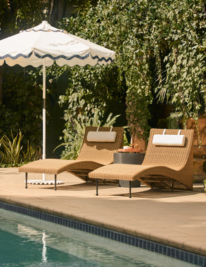 Two Marisol sculptural wicker outdoor chaise by Sarah Sherman Samuel and an umbrella by the poolside.