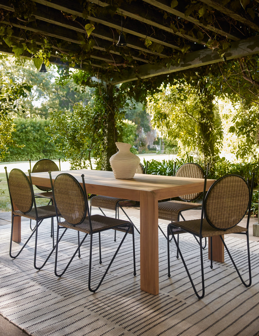 #color::natural | Six Ziggy modern wicker outdoor dining chair by Sarah Sherman Samuel surrounding a teak outdoor dining table under a pergola.