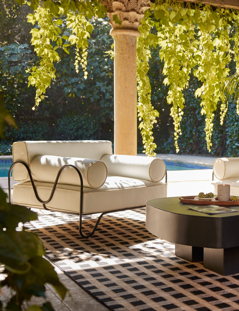 #color::ivory | An outdoor lounge space featuring the Peggy sculptural iron frame and white cushion outdoor accent chair.