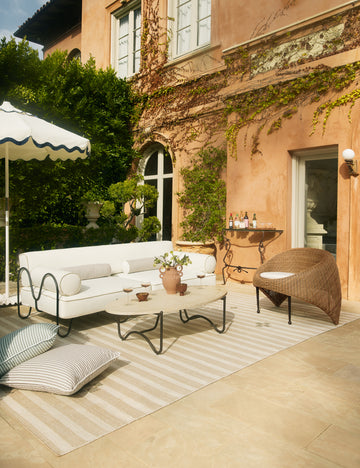 #color::faux-travertine | Outdoor patio space featuring the Peggy sculptural iron frame and stone top oval outdoor coffee table.
