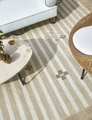 Orion handwoven neutral striped outdoor rug by Sarah Sherman Samuel styled with an outdoor coffee table and chairs.