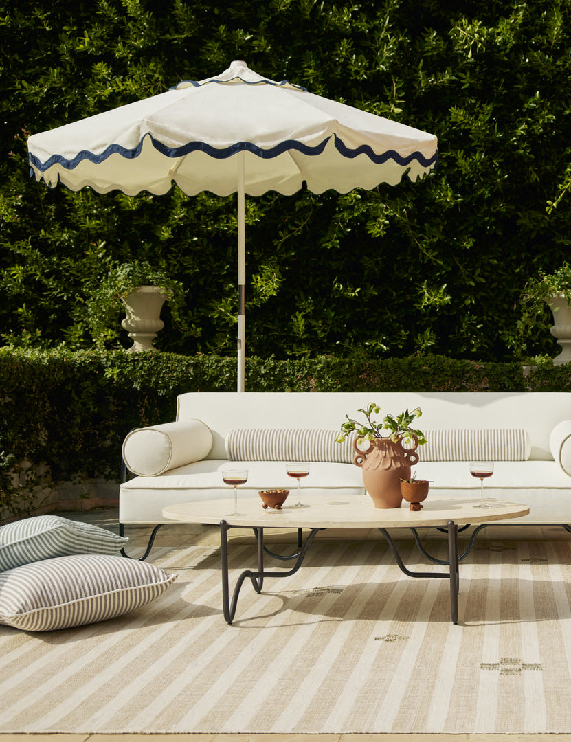 #color::ivory | Outdoor patio lounge space featuring the Peggy sculptural iron frame and stone top oval outdoor coffee table.