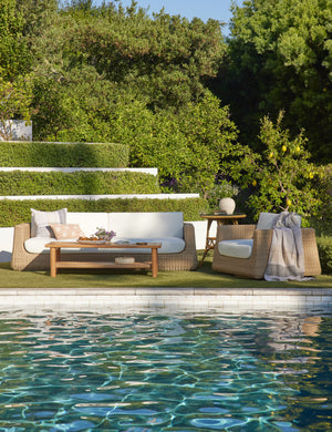 Gally teak and wicker outdoor coffee table styled with wicker outdoor sofa and swivel chair by the poolside.