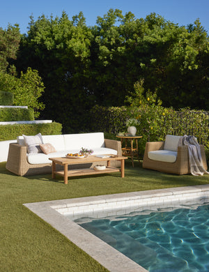 Aisha wide arm modern wicker outdoor swivel chair and sofa in a poolside lounge space.