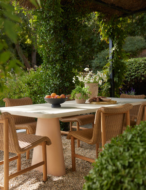 Six Gally wicker and teak outdoor dining chairs styled with a two-toned stone outdoor dining table.