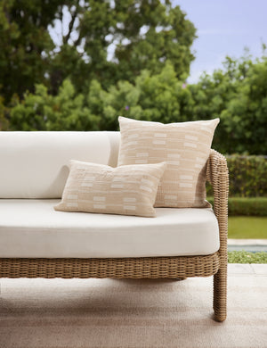 Two broken stripe pattern pillows styled on the Hadler modern sculptural open frame wicker outdoor sofa.