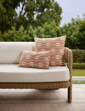 Both the leighton lumbar pillow and throw pillow in terracotta styled on an outdoor sofa together.