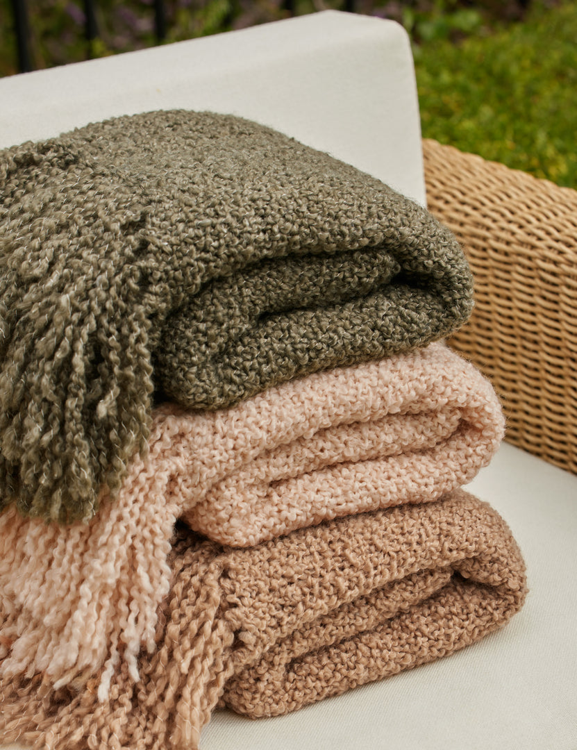#color::terracotta #color::moss #color::natural | All three colors of the Jaffe chunky knit fringed outdoor throw blanket folded and stacked on top of each other.