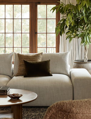 The Bryce natural-toned silk square pillow sits on a gray linen sofa with a brown velvet lumbar pillow