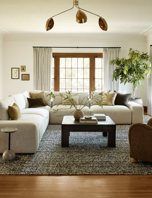 The Taos espresso rug lays in a living room under a square coffee table and an ivory sectional