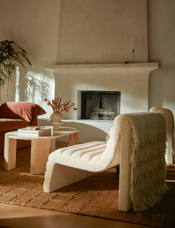 #color::ivory-boucle | Leon textural boucle channel tufted armless accent chair by Carly Cushnie styled with an oval stone coffee table.