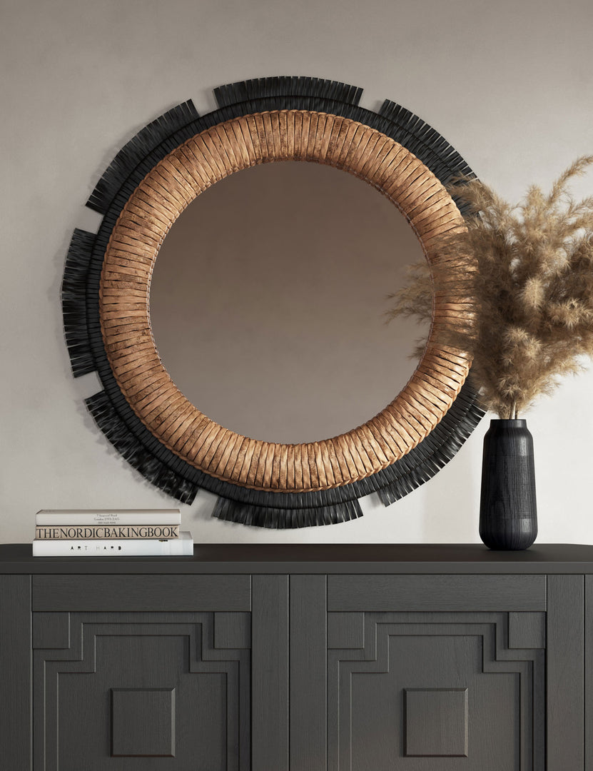 #color::black | Eloy round woven natural fiber wall mirror hung above a black console table.