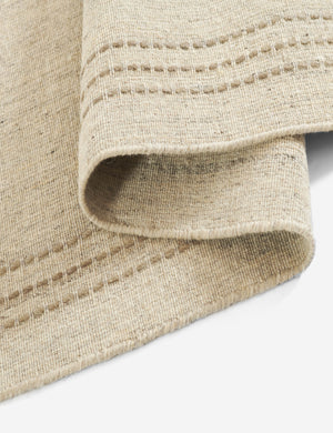 Close up of the edge of the Greco low pile wool rug with accent border stitching.