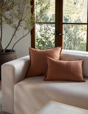 The arlo Burnt Orange flax linen pillow in its lumber and square sizes sit together on a natural linen sofa