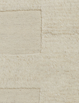 Close up of the Raita subtle bar patter fringe area rug in ivory