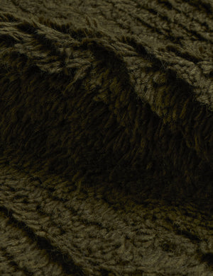 Close up of the Raita subtle bar patter fringe area rug in moss green