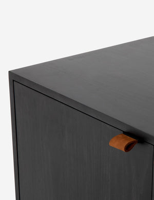 Close-up of the top and pulls of the Rosamonde black wood sideboard with brown leather pulls and a metal base