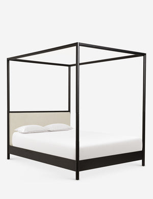 Angled view of Simonette black canopy bed with upholstered headboard