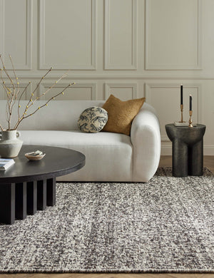 The Taos espresso rug lays in a living room with accented walls under a round coffee table and an ivory sectional